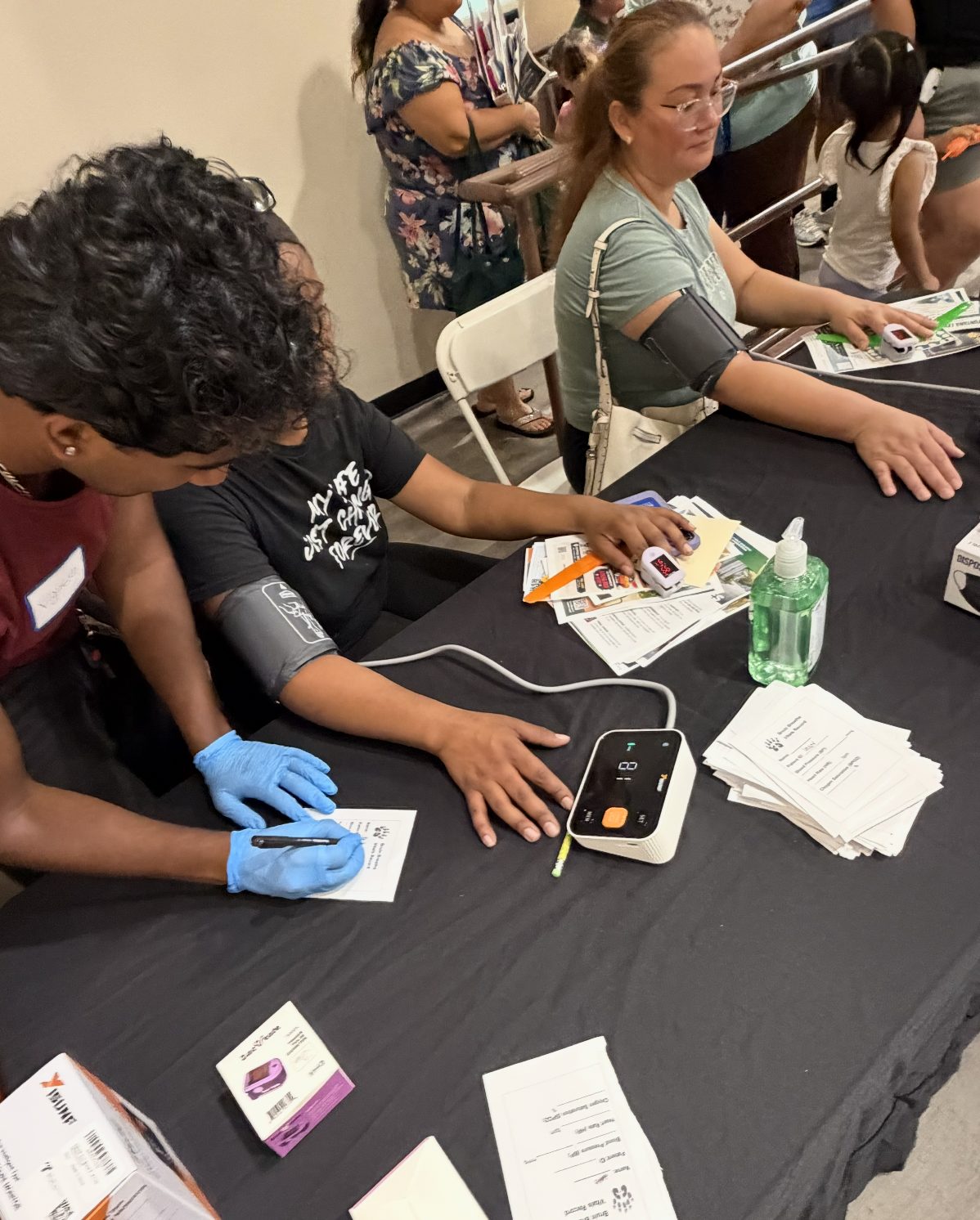 A volunteer checking a patient's blood pressure at a screening event